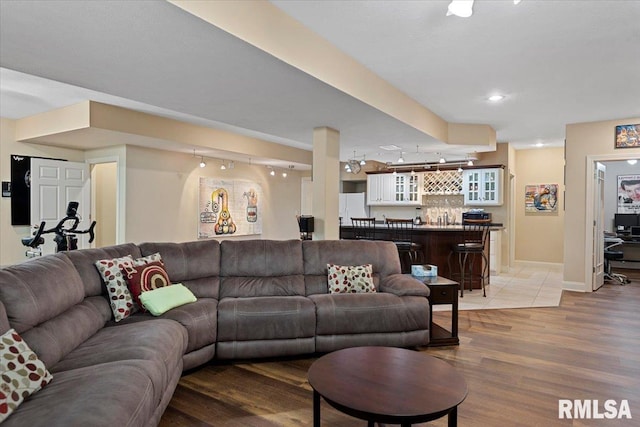 living room featuring baseboards, light wood-type flooring, bar, and recessed lighting
