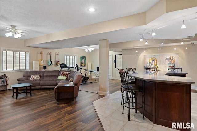 living room featuring light wood finished floors, baseboards, a ceiling fan, and a healthy amount of sunlight