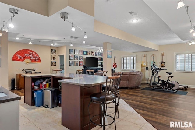 kitchen with light tile patterned floors, visible vents, open floor plan, a kitchen breakfast bar, and a kitchen island