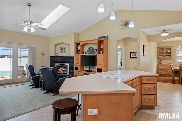 kitchen with a ceiling fan, light tile patterned floors, visible vents, open floor plan, and a lit fireplace
