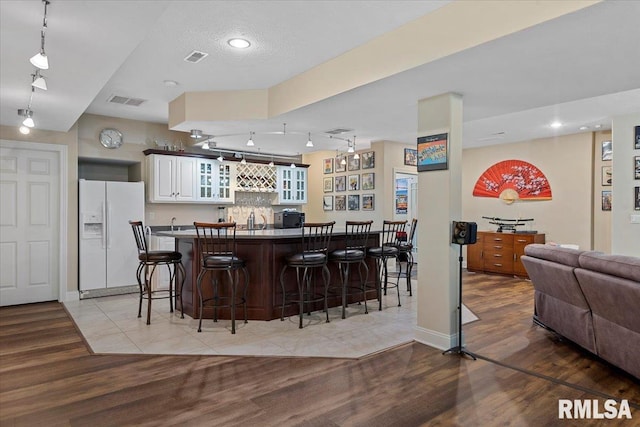 bar with white fridge with ice dispenser, indoor bar, light wood finished floors, and visible vents