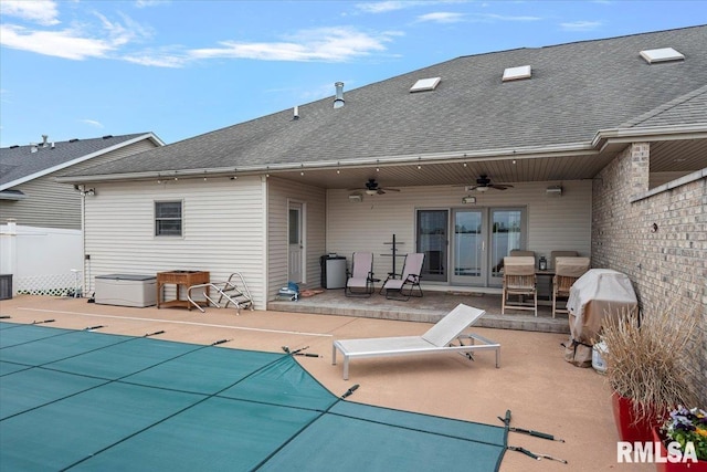 back of property featuring a ceiling fan, fence, a covered pool, a patio area, and roof with shingles