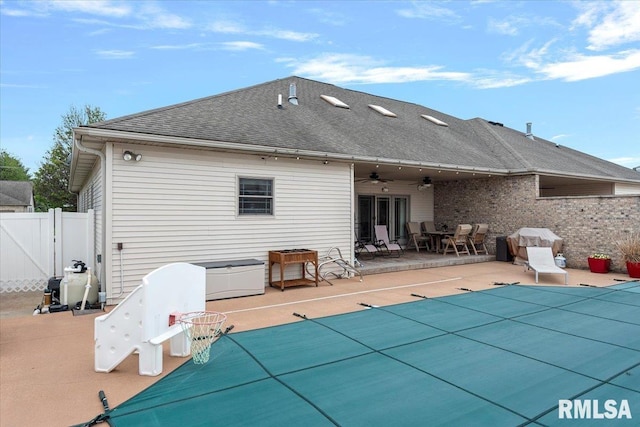 rear view of house with a ceiling fan, a fenced in pool, fence, a patio area, and a gate