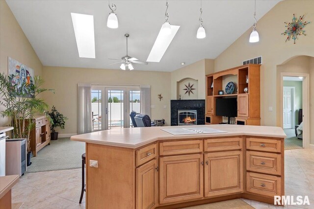 kitchen with a center island, light countertops, a glass covered fireplace, and a skylight