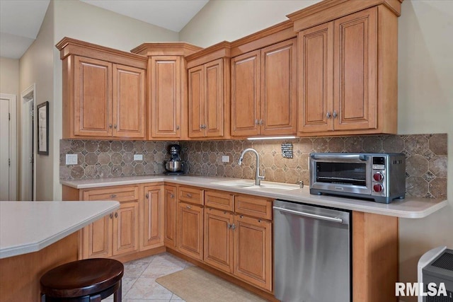 kitchen with light countertops, a sink, a kitchen breakfast bar, backsplash, and dishwasher