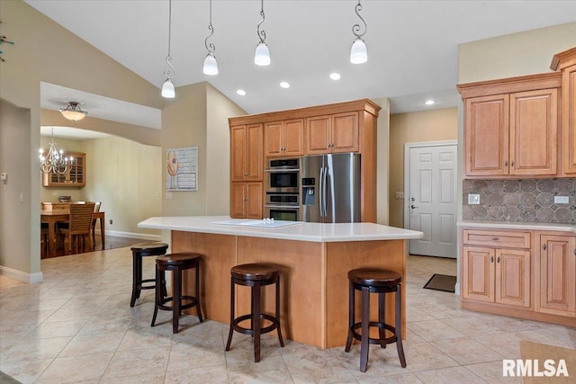 kitchen with decorative backsplash, a notable chandelier, a breakfast bar area, and appliances with stainless steel finishes