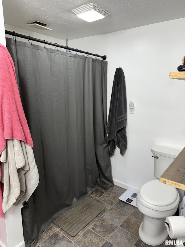 176 Lakeview Dr, Wataga, IL 61488 - bathroom with baseboards, toilet, a textured ceiling, a shower with curtain, and stone finish floors