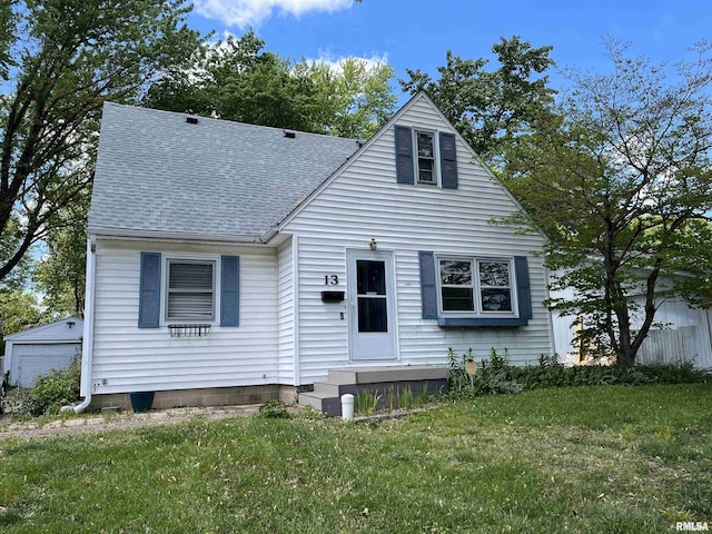 view of front facade with a shingled roof and a front lawn