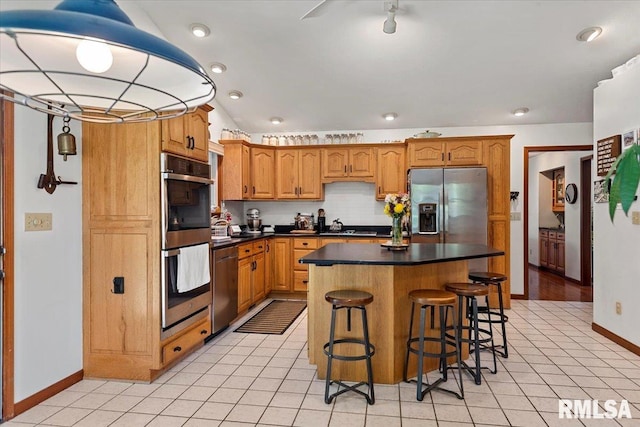 1405 Woods Farm Ln, Springfield, IL 62704 - kitchen with stainless steel appliances, baseboards, a center island, dark countertops, and a breakfast bar area