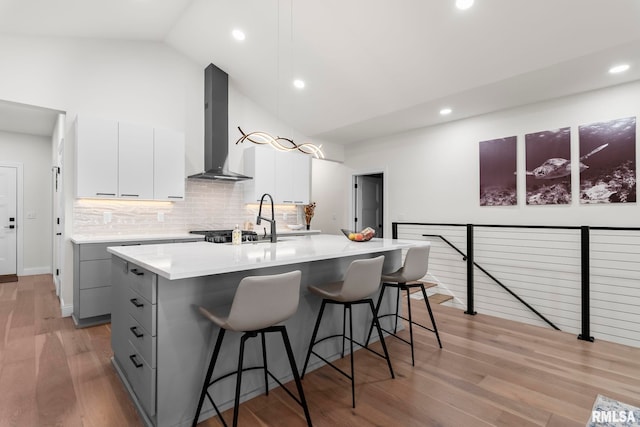 321 Harbor Point Pl, Springfield, IL 62712 - kitchen with wall chimney range hood, gray cabinetry, a sink, a kitchen bar, and decorative backsplash