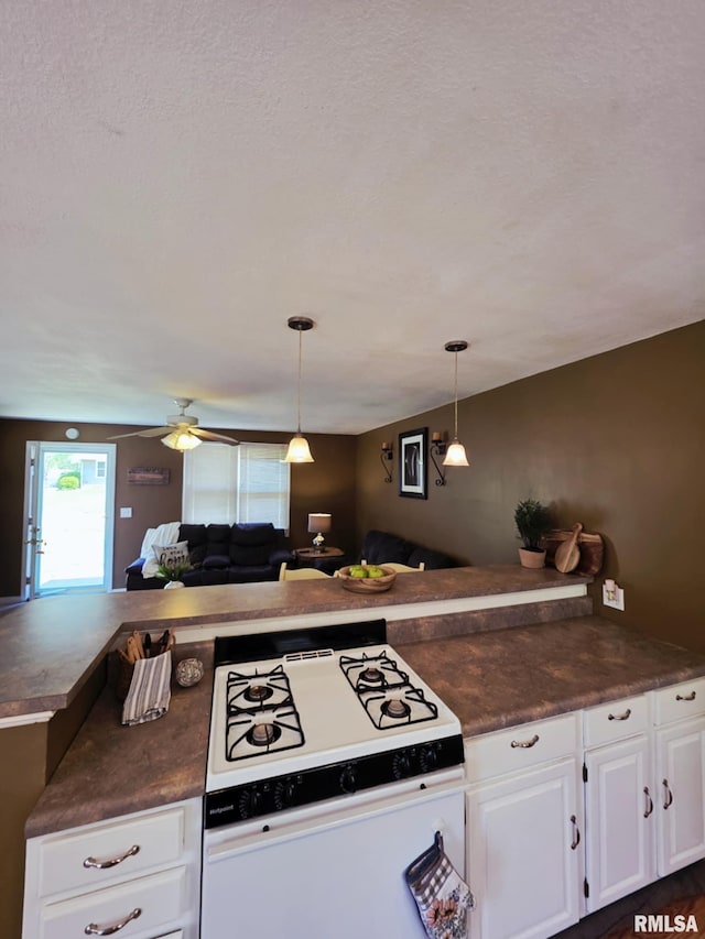 514 W Washington St, Mendon, IL 62351 - kitchen featuring white range with gas stovetop, dark countertops, white cabinets, open floor plan, and ceiling fan