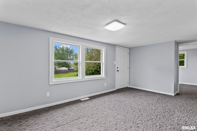 spare room with a textured ceiling, carpet flooring, and baseboards