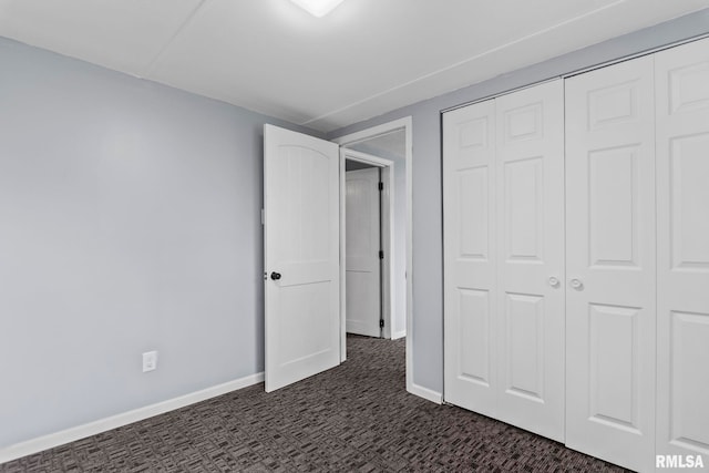 unfurnished bedroom featuring a closet, baseboards, and dark carpet