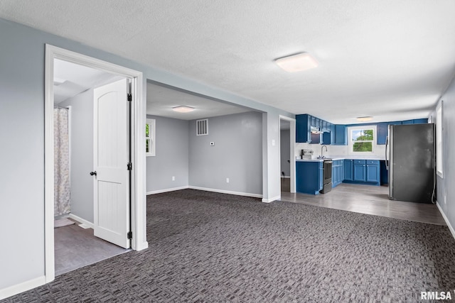 kitchen featuring blue cabinets, stainless steel appliances, light countertops, dark colored carpet, and baseboards
