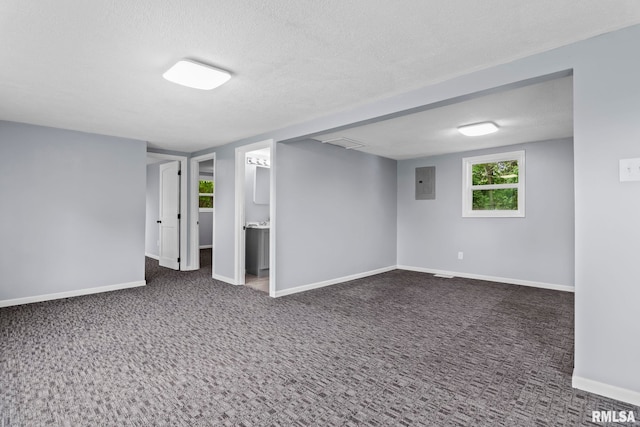 basement featuring electric panel, baseboards, carpet floors, and a textured ceiling