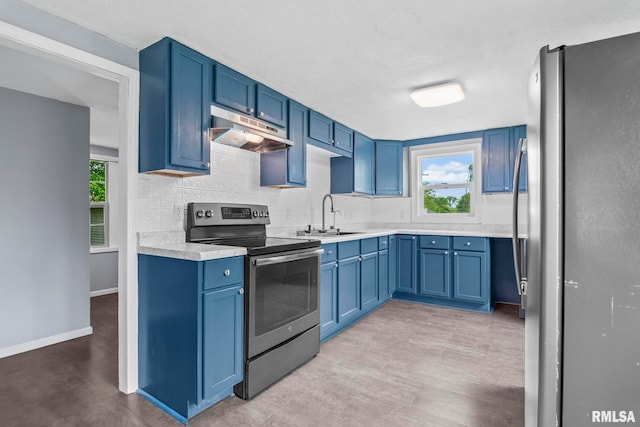 kitchen featuring appliances with stainless steel finishes, under cabinet range hood, a sink, light countertops, and healthy amount of natural light