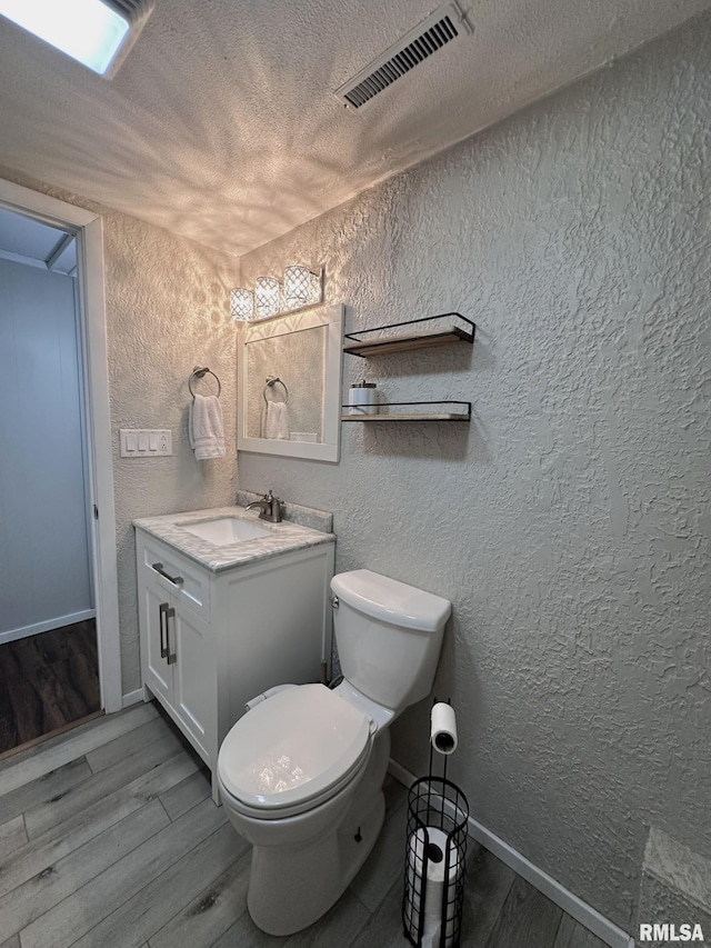 209 Brookview Dr, Abingdon, IL 61410 - bathroom with a textured wall, wood finished floors, baseboards, toilet, and vanity