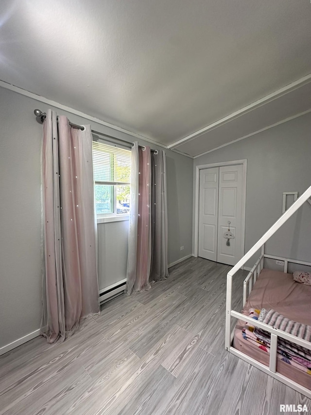 209 Brookview Dr, Abingdon, IL 61410 - unfurnished bedroom featuring a baseboard heating unit, light wood-type flooring, vaulted ceiling, and baseboards