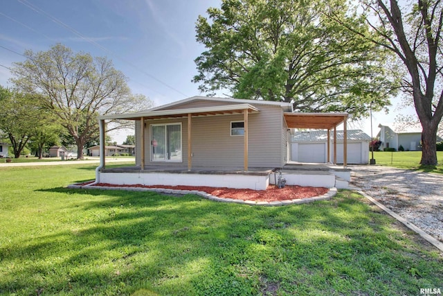 view of front facade featuring a front yard, an outbuilding, driveway, and covered porch