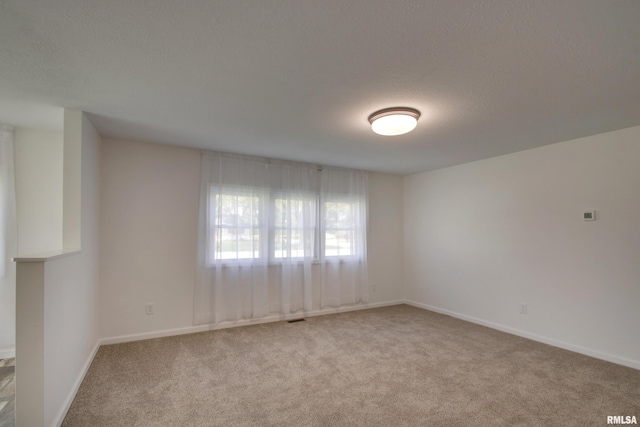 empty room featuring light carpet and baseboards