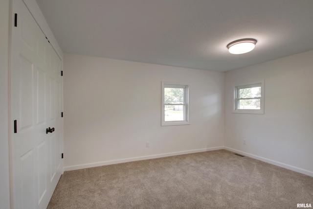 unfurnished room with light carpet and baseboards