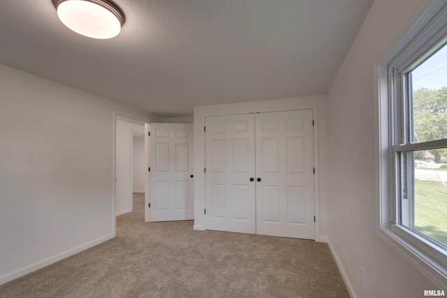 unfurnished bedroom with baseboards, carpet, a closet, and a textured ceiling