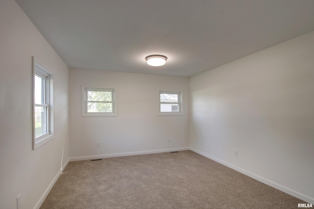 unfurnished room featuring light colored carpet and baseboards