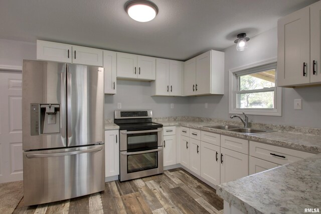 kitchen with stainless steel appliances, a sink, light countertops, and white cabinetry
