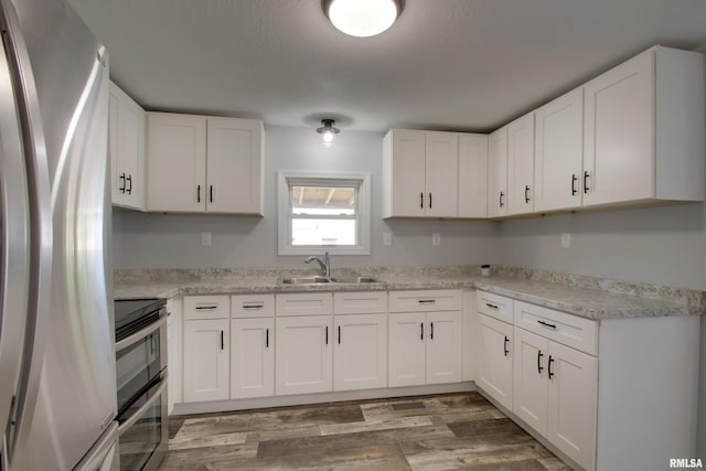 kitchen with stainless steel appliances, a sink, light wood-style floors, light countertops, and white cabinets