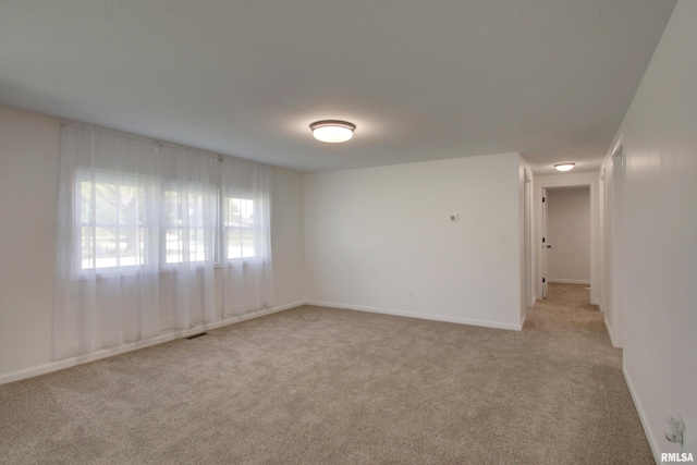 empty room featuring light colored carpet and baseboards