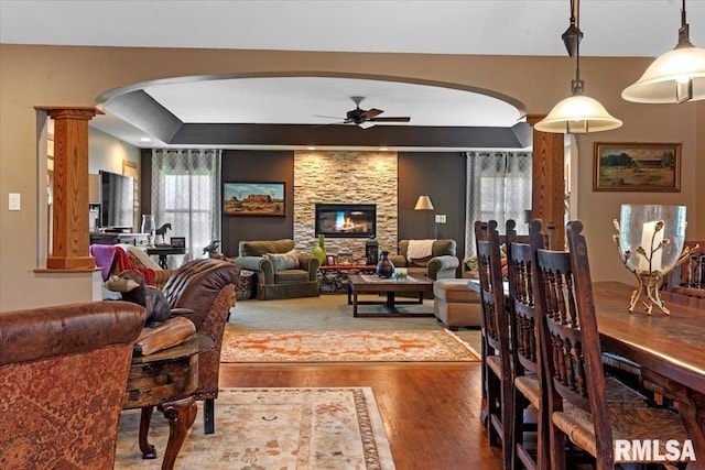 living room featuring arched walkways, a ceiling fan, wood finished floors, and plenty of natural light
