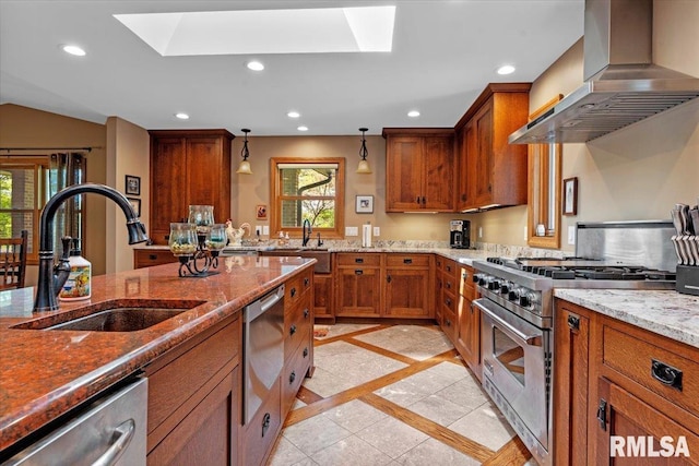 kitchen featuring appliances with stainless steel finishes, wall chimney exhaust hood, a sink, brown cabinetry, and inlaid floor details