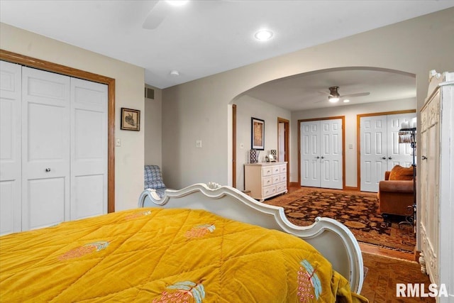 bedroom with arched walkways, two closets, ceiling fan, and recessed lighting