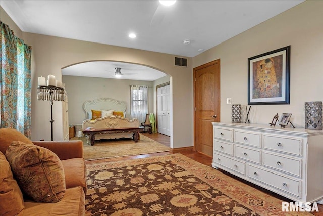bedroom featuring arched walkways, light wood-style floors, baseboards, and recessed lighting