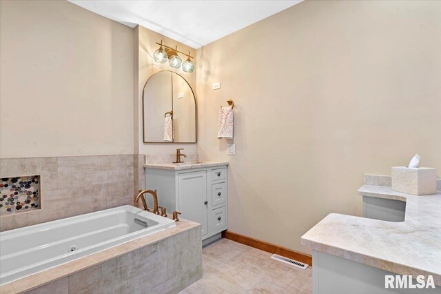 bathroom with vanity, a tub with jets, and baseboards