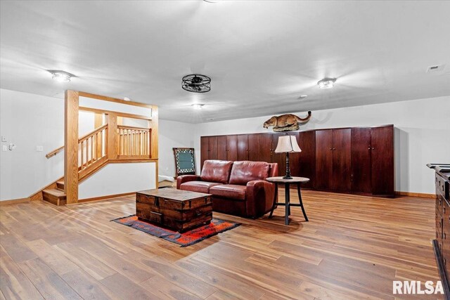 living room with light wood-type flooring, stairway, and baseboards