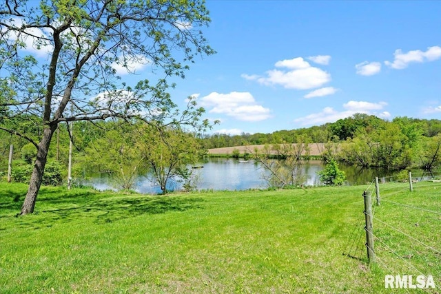 water view featuring a forest and fence