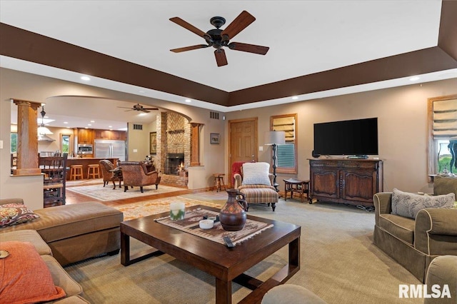 living area with ceiling fan, recessed lighting, light carpet, ornate columns, and a large fireplace