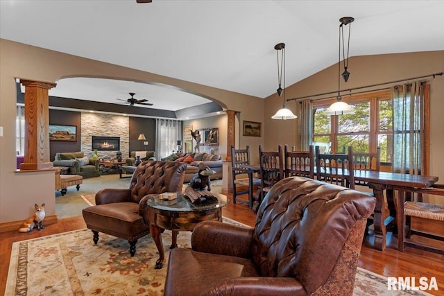 living room with decorative columns, arched walkways, a ceiling fan, wood finished floors, and lofted ceiling