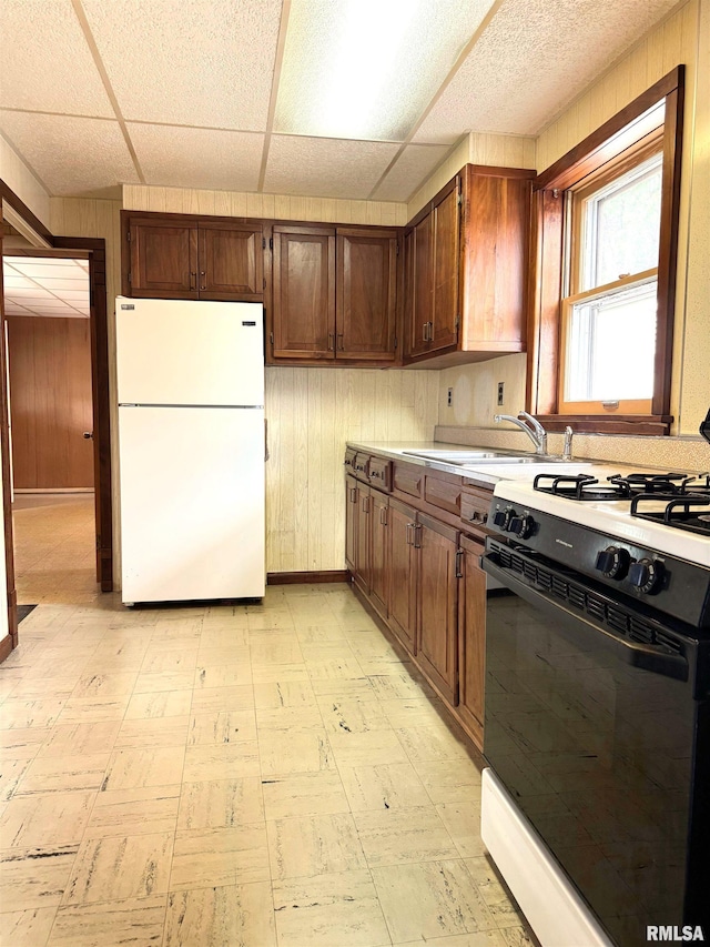 461 W Fremont St, Galesburg, IL 61401 - kitchen with freestanding refrigerator, black gas range oven, wooden walls, light flooring, and a sink