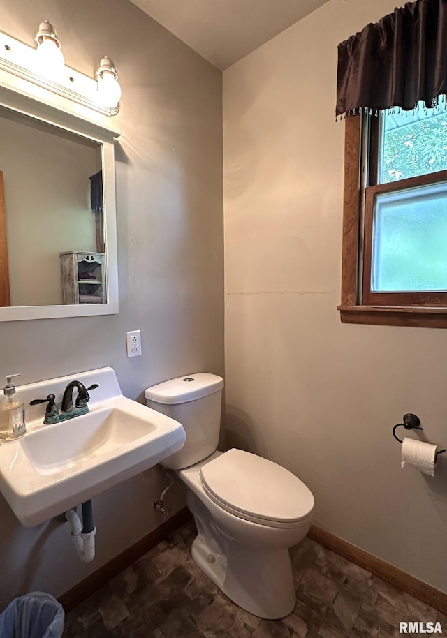810 NW 7th Ave, Galva, IL 61434 - half bathroom featuring toilet, baseboards, stone finish flooring, and a sink