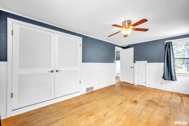 2255 N Broad St, Galesburg, IL 61401 - unfurnished bedroom featuring wainscoting, wood finished floors, a closet, crown molding, and ceiling fan