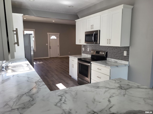718 Adams St, Quincy, IL 62301 - kitchen with appliances with stainless steel finishes, a sink, decorative backsplash, white cabinets, and dark wood-style flooring