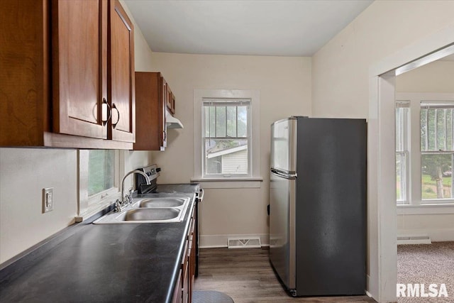 708 E 5th St, Pana, IL 62557 - kitchen featuring stainless steel appliances, under cabinet range hood, brown cabinetry, and healthy amount of natural light