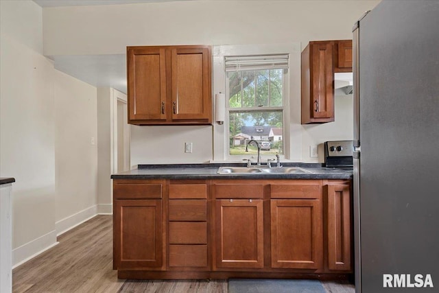708 E 5th St, Pana, IL 62557 - kitchen with freestanding refrigerator, range hood, light wood finished floors, and brown cabinets