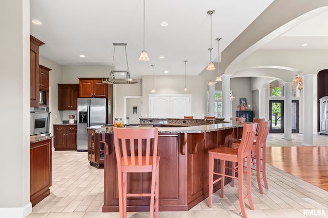 4901 Wildcat Run, Springfield, IL 62711 - kitchen featuring appliances with stainless steel finishes, arched walkways, decorative columns, recessed lighting, and a breakfast bar