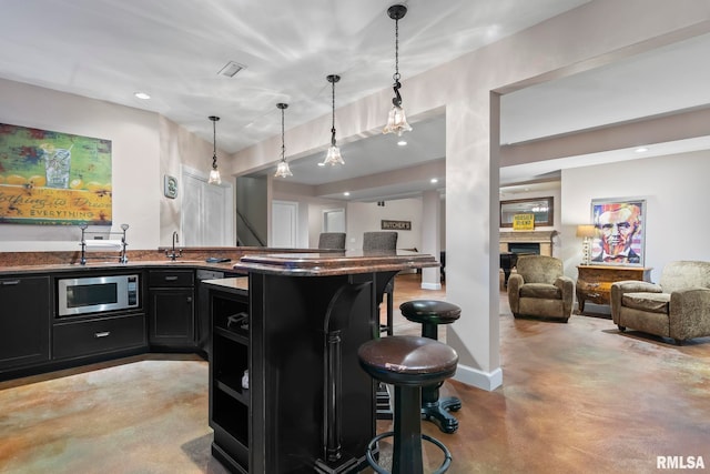 4901 Wildcat Run, Springfield, IL 62711 - bar with stainless steel microwave, concrete floors, a fireplace, decorative light fixtures, and a sink