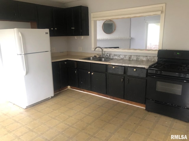 1522 Rim Rd, Quincy, IL 62305 - kitchen with freestanding refrigerator, black range with gas cooktop, a sink, light flooring, and dark cabinetry
