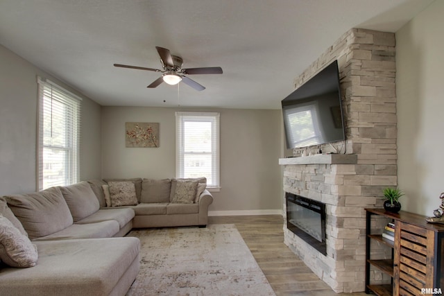 801 S 22nd St, Quincy, IL 62301 - living area with light wood-style floors, a stone fireplace, a ceiling fan, and baseboards
