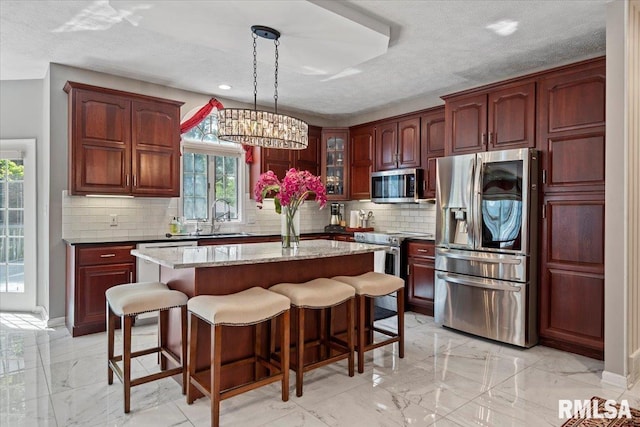 505 Clipper Rd, Springfield, IL 62704 - kitchen featuring stainless steel appliances, a sink, light marble finish floors, a kitchen breakfast bar, and a center island